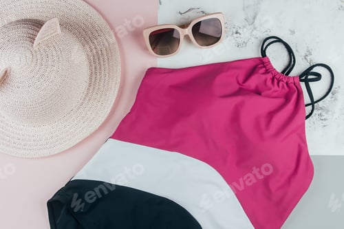 Preview: Woman's beach accessories: one-piece swimsuit, sunglasses and hat on backround. Flat lay, top view.