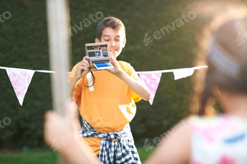 Preview: Boy photographing girl using instant camera