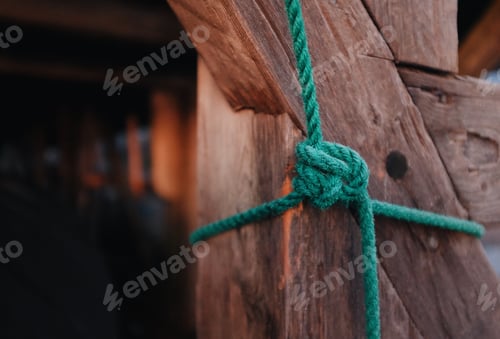 Preview: detail of a knot on a green rope tied around wooden timber