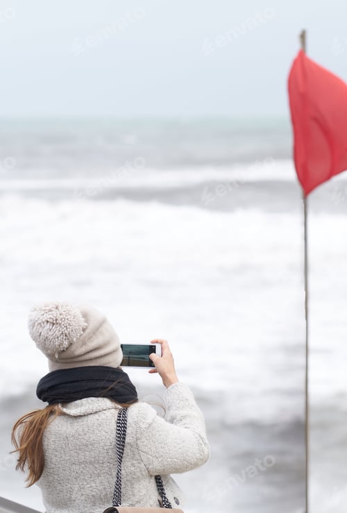 Preview: Woman Photographs the Ocean by Red Flag