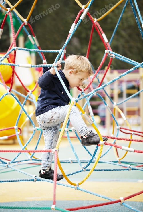 Preview: Happy little boy climbing on playground equipment