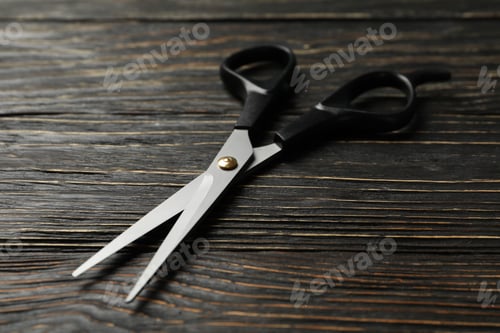 Preview: Black hairdresser scissors on wooden background, close up
