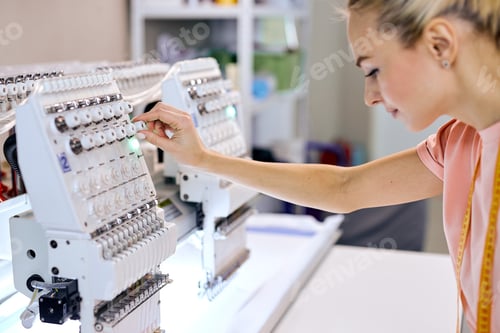 Preview: confident seamstresses in modern studio workshop, preparing tailoring machine for work