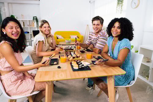 Preview: Multiethnic group of young friends meeting at home and eating sushi