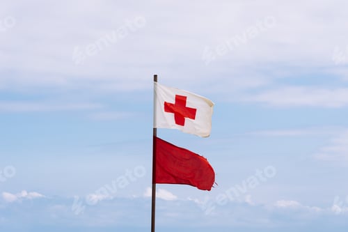 Preview: Rescue red cross flag and red flag waving against sky in the beach