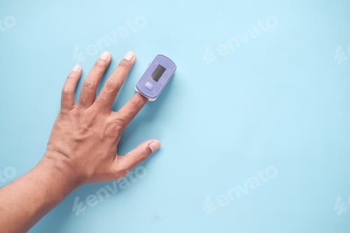 Preview: close up of man hand using pulse oximeter on blue background
