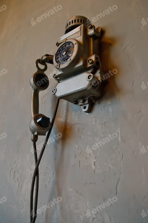 Preview: Old vintage wired telephone for communication hangs on textured gray wall