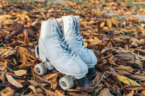 Preview: Quad roller skates rest on a pile of yellow leaves evoking a sense of autumn. A pair of skate boots.