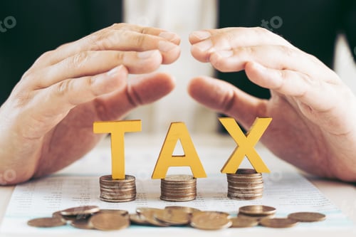 Preview: Businessman's hand is protecting letters with the word tax on a coin. Tax concept.