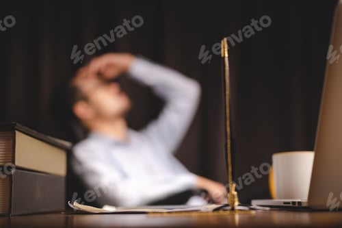 Preview: Closeup of a pen attached to a chain in stand lying on desk near laptop and books with documents