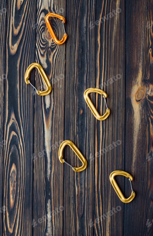 Preview: Five objects. Isolated photo of climbing equipment. Parts of carabiners lying on the wooden table