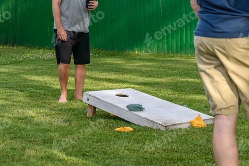 Preview: Guys playing cornhole game in backyard