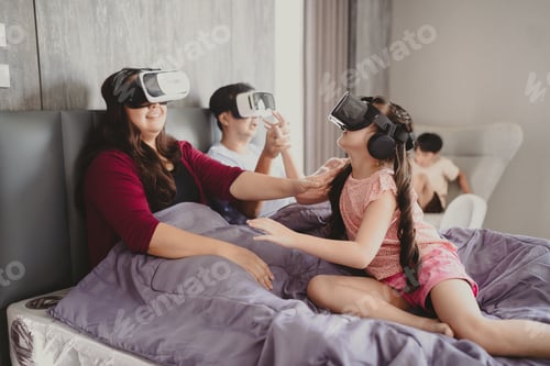 Preview: Smiling and cheerful and playful young Asian family of mother father playing on VR technology