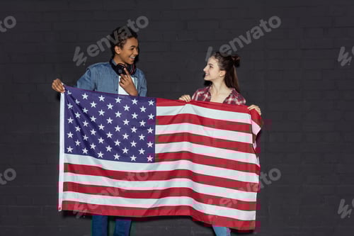 Preview: happy teen couple with usa flag and looking at each other on black