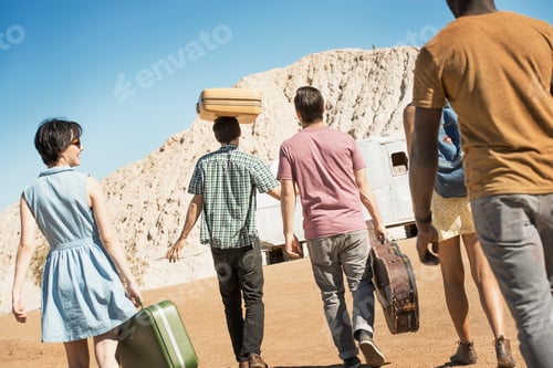 Preview: A group of people walking in a line in open desert country, carrying their cases, on a road trip.