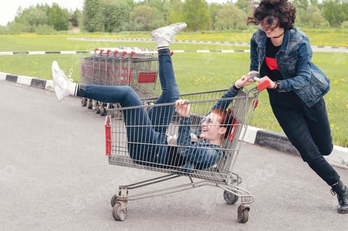 Preview: ↟ Funny happy teenage girls in denim clothes have fun and ride on the shopping cart