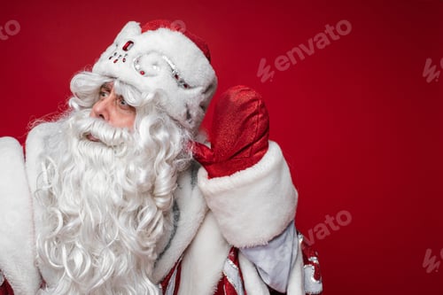 Preview: portrait of father frost in long warm coat, red mittens and a hat hears someone
