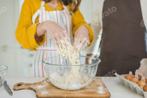 Preview: Young couple making dough in kitchen together