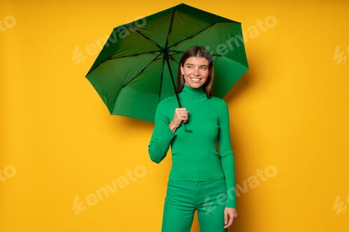 Preview: Woman walking on fall rainy day under waterproof umbrella on yellow studio background