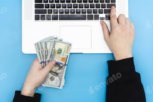 Preview: Laptop and money in male hands, top view.