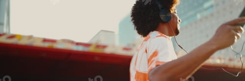 Preview: man wearing shirt listening to music in headphones and dancing on urban city background