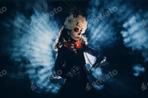 Preview: Woman with mexican skull halloween makeup in dark with backlight rays.