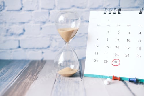 Preview: hourglass flowing through the bulb of sandglass and calendar on table