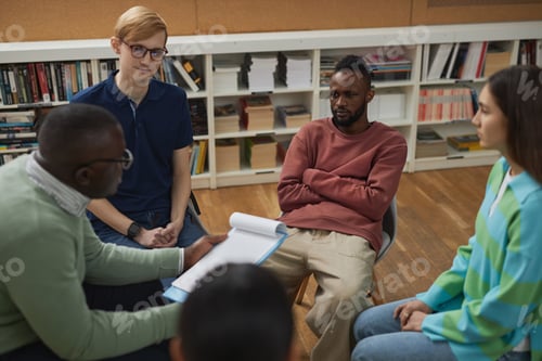 Preview: Group of young people sitting in circle during therapy session in college