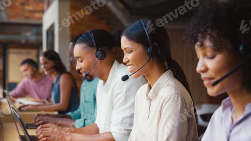 Preview: Multi-Cultural Customer Support Or Telesales Team In Modern Open Plan Office Wearing Headsets