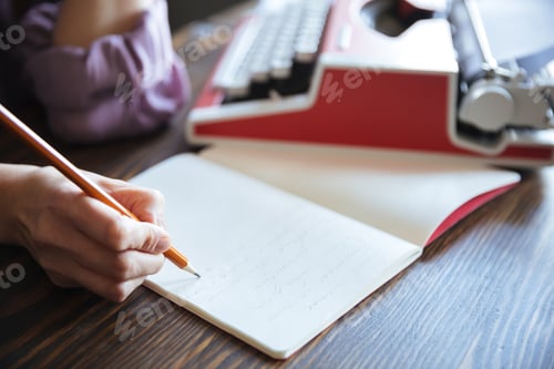 Preview: Portrait of a female hand holding pencil over open notebook