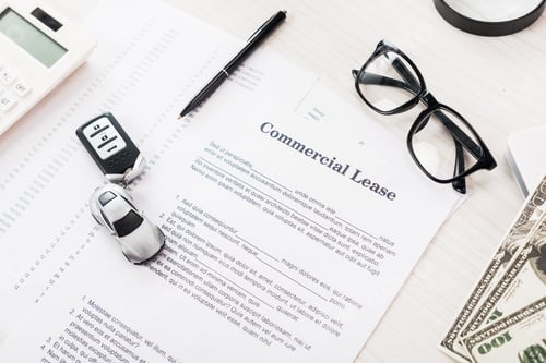 Preview: top view of document with commercial lease lettering near toy car, pen, money and glasses