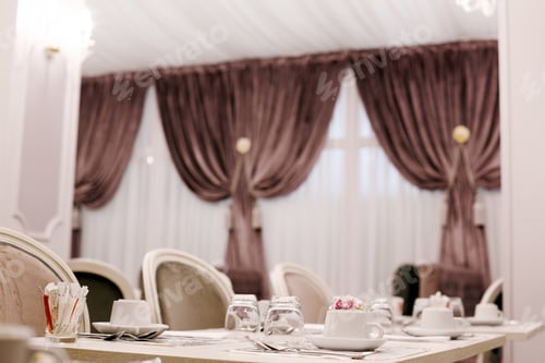 Preview: The table is served for Breakfast in a cozy bright dining room with large Windows and dark curtains