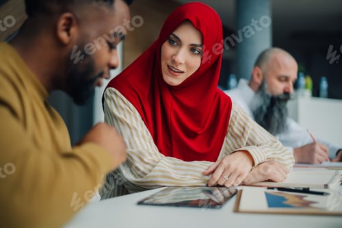 Preview: Muslim businesswoman wearing hijab discussing business strategy with african american businessman