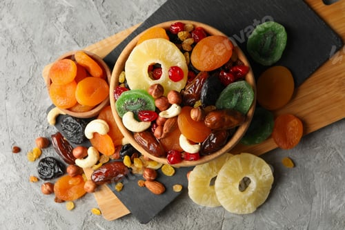 Preview: Board and bowls with dried fruits and nuts on gray background