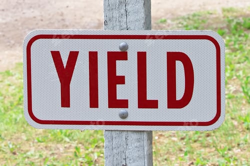 Yield Sign on Post in Grassy Rural Area