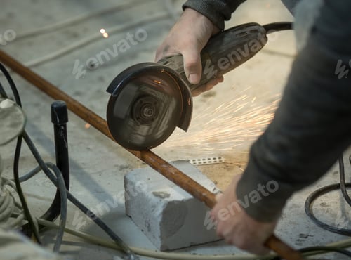 Preview: a man with a beard cuts a metal profile indoors with an angle grinder, sparks fly