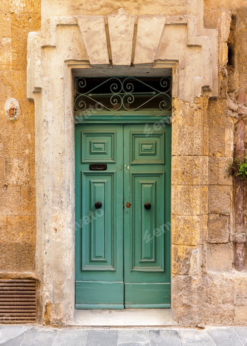 Preview: Vertical shot of a vintage green front door of a yellow brick building in Valetta, Malta