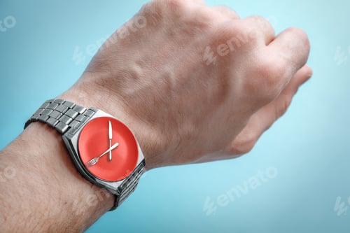 Preview: Wrist watch on man's hand. Plate, knife and fork on clock face. Concept of intermittent fasting