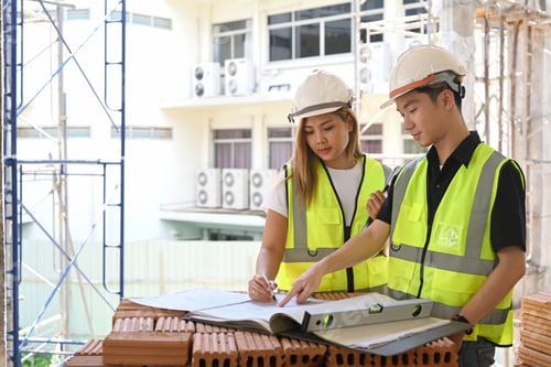 Preview: Female architects discussing with engineer about their project at construction site.