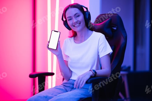 Cheerful Woman Displaying Phone Wearing Headphones in Home