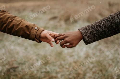 Preview: A tender touch between two hands against a blurred natural backdrop.