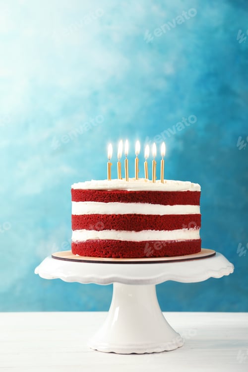 Preview: Delicious homemade red velvet cake with candles on table against color background