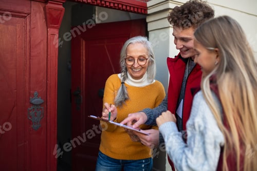 Preview: Young door to door volunteers talking to senior woman and taking survey at her front door