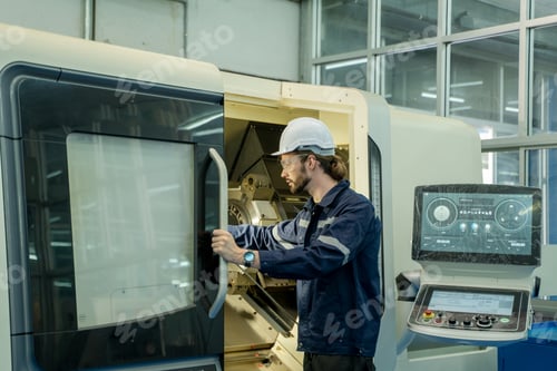 Preview: Engineer using laptop computer controlling automated robot hand with CNC machine in smart factory.