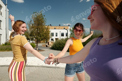 Preview: Happy cute girlfriends in casualwear making pile of hands and having fun