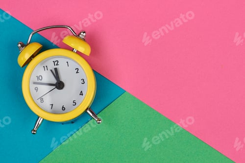 Preview: Yellow alarm clock on multicolored background.