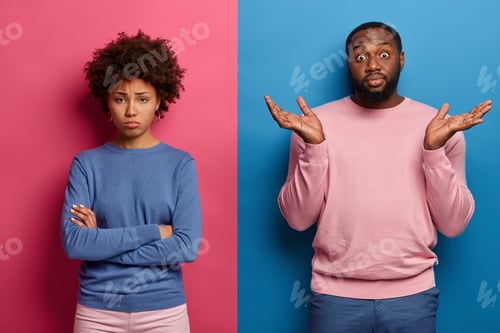Preview: Hesitant black man spreads palms with hesitation, doesnt know how to calm girlfriend who stands offe