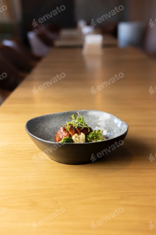Preview: grey bowl filled with a delicious dish of roasted pork belly with cauliflower, broccoli