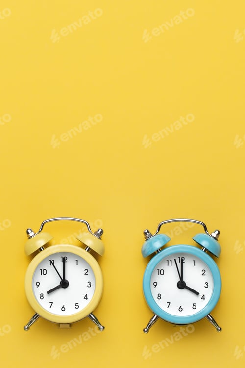 Preview: Two round alarm clocks yellow and blue on the yellow background.