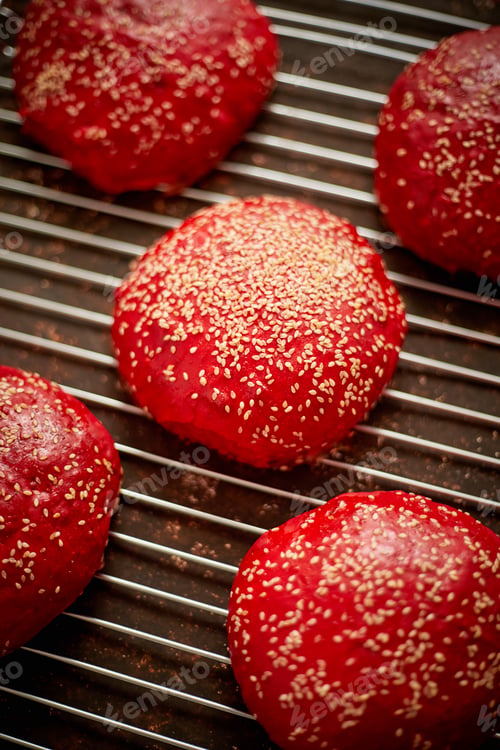 Preview: Fresh baked red homemade burger buns with sesame top view. Placed on metal grill